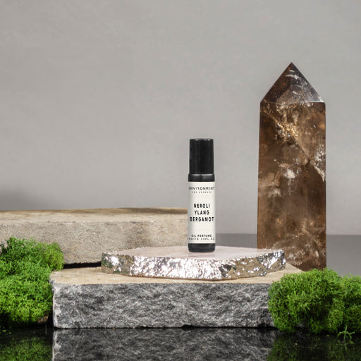 Small bottle with a label on a stone surface next to a crystal, with a gray background