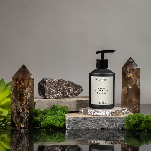 Baies Hand Soap on a stone surface, surrounded by greenery and crystals.