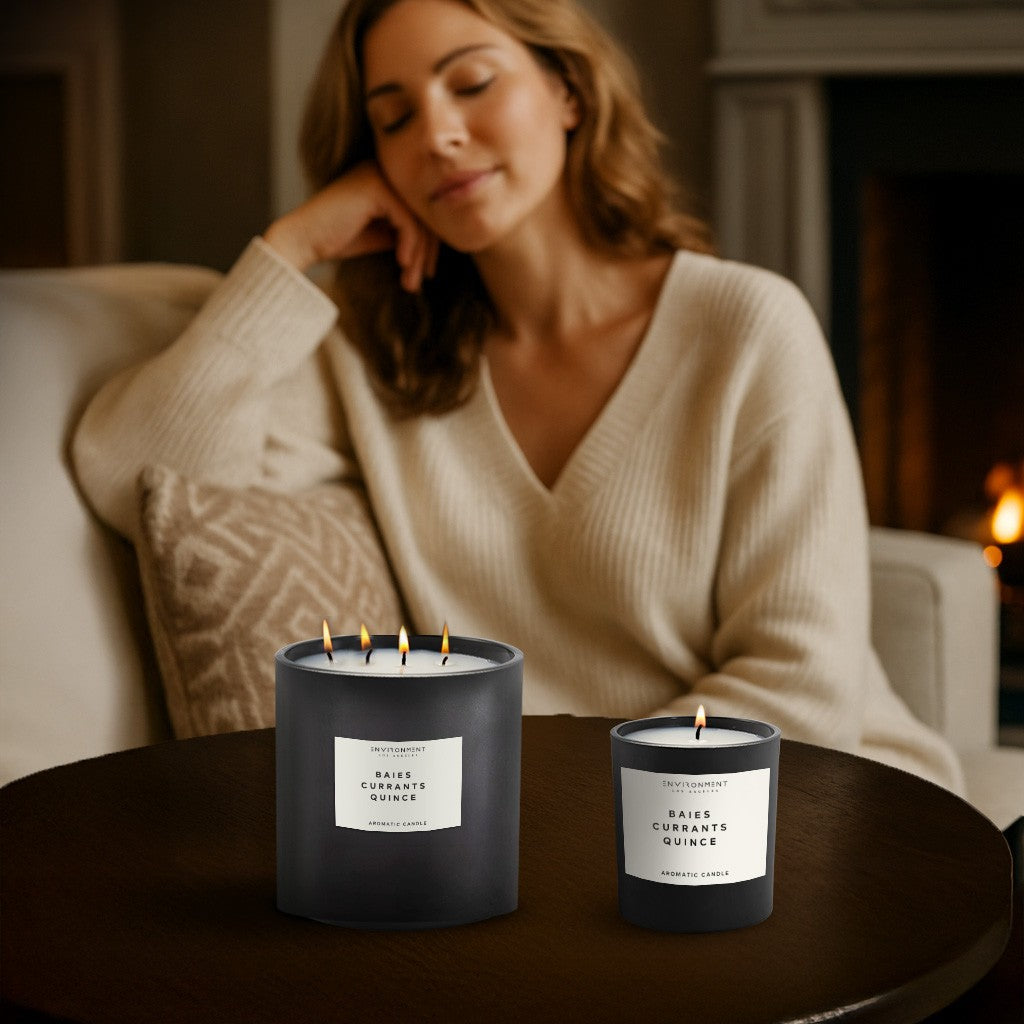 Woman sitting on a couch with two lit Baies Candles 